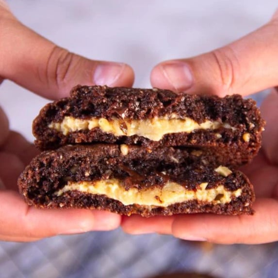 hands holding cookie broken to show passionfruit and chocolate filling
